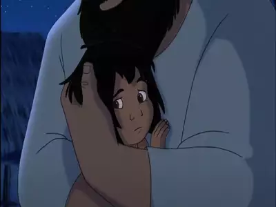 Mowgli looks emotional as he is held in a protective embrace by a father figure in a nighttime village setting.