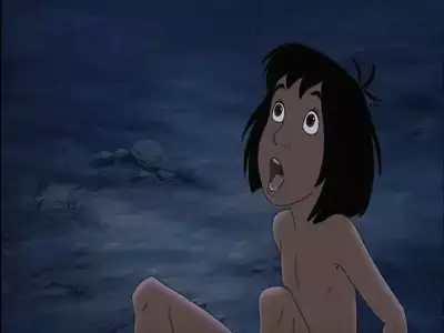 Mowgli sits on the ground, looking up in shock under a dark blue night sky in The Jungle Book 2.