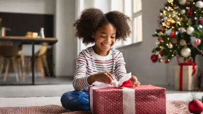 Illustration of a little girl with eyes wide open, joyfully unwrapping a gift, capturing the magical moment of surprise and wonder